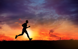 The silhouette of a man running in front of a sunset