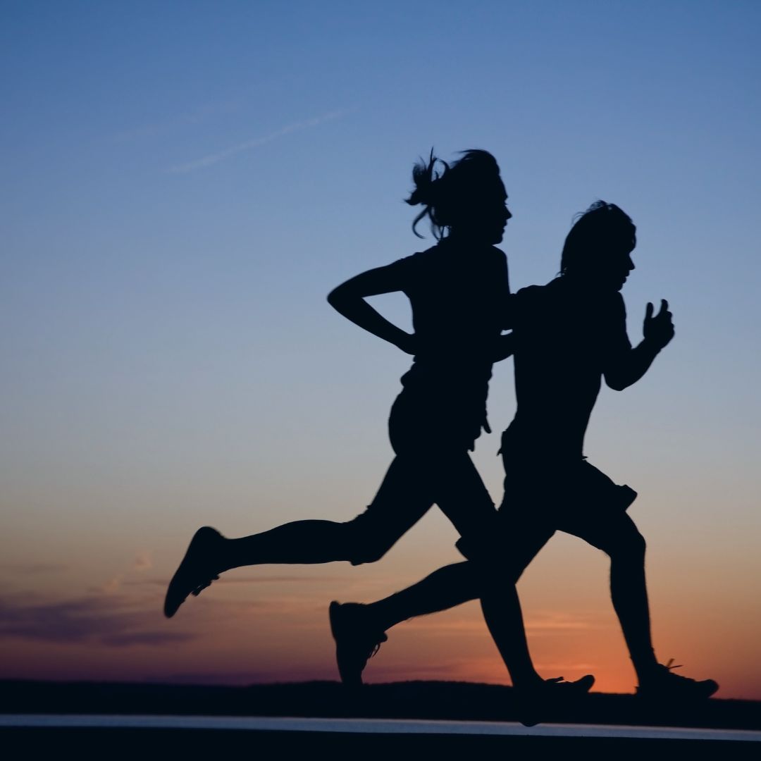 Silhouettes of two runners at sunset