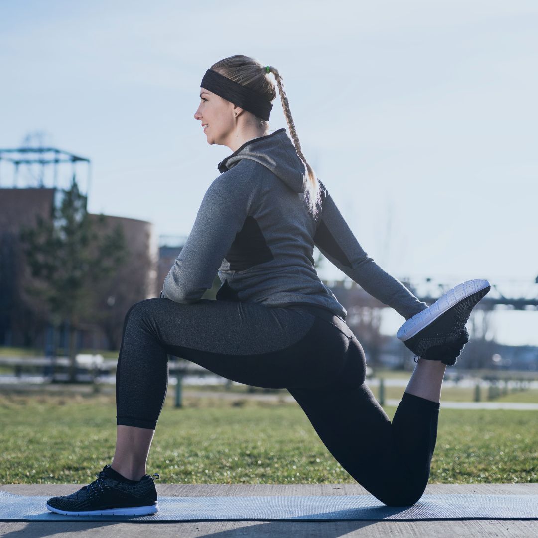 Woman stretching her quads to help prevent lower back pain while running