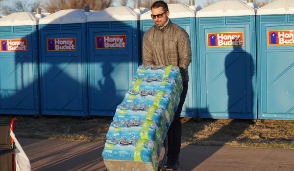 Volunteer moving stacks of bottled water cases with a dolly